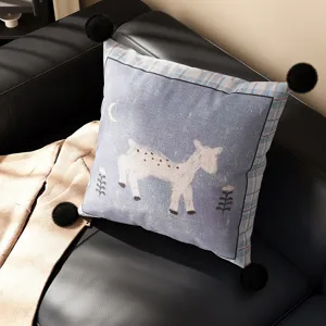 Detailed shot of the cartoon animal cushion showing the deer pattern and fluffy black pom poms.