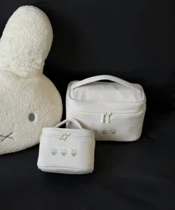 Close-up detail of canvas cosmetic bag set with delicate embroidered clover flower pattern.