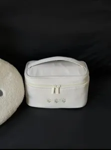 Close-up view of the portable white makeup storage bag showcasing delicate floral embroidery.