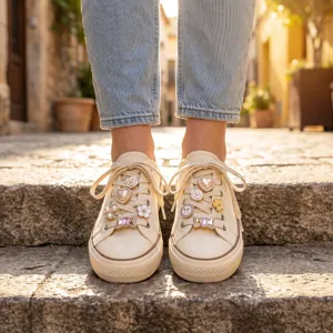 Détail de baskets en toile avec charmants lacets ornés de perles de strass et de camélias.