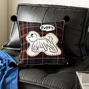 Detailed view of a brown plaid throw pillow with black pom-poms and cute puppy pattern for sofa.