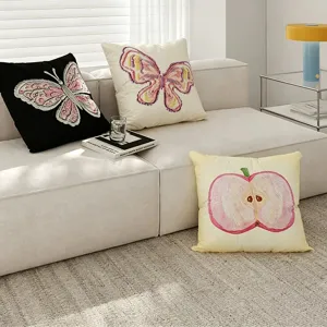 Detailed showcase of embroidered butterfly and apple decorative throw pillows on modern sofa.