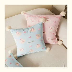 Cozy cream style plush throw pillow with cute rabbit print and fluffy corner pom poms for sofa.