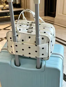 Vista dettagliata della borsa cosmetica a pois bianchi e neri con fascia per valigia.