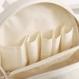 Vue intérieure détaillée d'une trousse de maquillage blanche avec compartiments multiples.