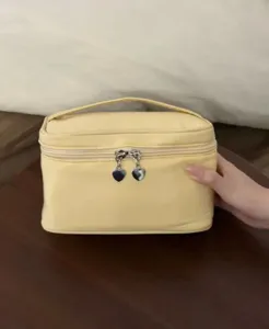 Yellow cosmetic bag detail, featuring heart zipper pulls and handle, convenient daily storage.