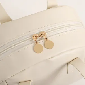 Vue de detail rapprochee de la fermeture eclair et des tirettes en metal beige.