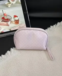 Pink polka dot makeup bag detail view, portable cosmetic pouch with zipper for travel use.