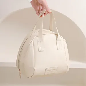 Vue détaillée de la trousse de toilette beige, montrant sa texture cuir et sa poignée.