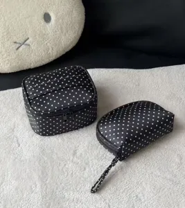 Detailed view of black and white polka dot cosmetic makeup bag with secure zipper closure.