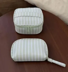 Detail view of green and white striped cosmetic bags set, showing texture and dual styles.