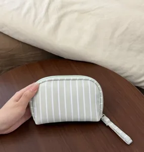 Close-up of green and white striped cosmetic pouch detail, showing fabric and zipper.