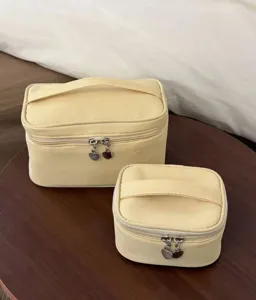 Detail view of yellow cosmetic travel storage bags set on wooden table, close-up zippers.
