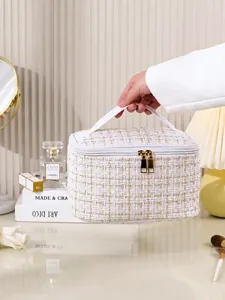 Elegant tweed cosmetic bag with top handle and gold zipper, stylish vanity storage case.