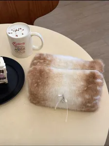 Cute plush cosmetic bag detail view showing soft gradient fur finish and delicate bow pendant.