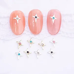 Vue détaillée de charms d'art d'ongle étoile à quatre branches en métal avec des strass étincelants.
