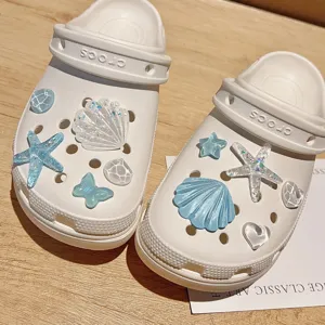 Sabots blancs avec de charmants breloques de chaussures marines bleues, parfaits.