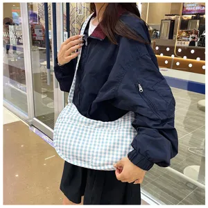 Close-up detail of a stylish blue and white plaid crescent shoulder bag worn in daily life.
