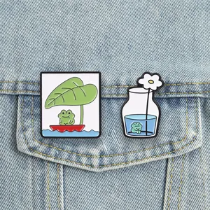 Close-up detail of cute cartoon frog enamel pins, green leaf boat and flower bottle brooch.