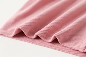 Close-upweergave van zachte roze geribbelde gebreide stoftextuur, met fijne details en gezellige warmte.