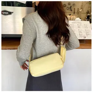 Gedetailleerd overzicht van de gele cilindrische crossbodytas in een gezellig café.