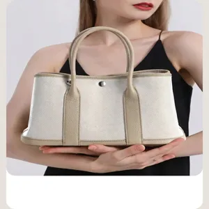 Detail view of the canvas handbag showing sturdy dual top handles and center snap closure.