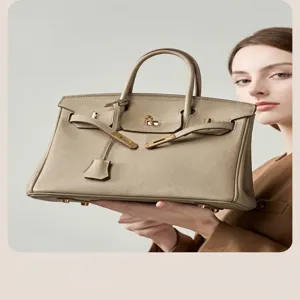 Elegant top handle handbag detail showing premium leather texture, metallic lock and straps.