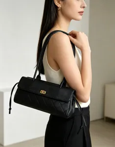 Detailed view of a stylish black genuine leather quilted baguette shoulder bag on model.