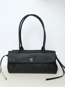 Detailed view of the black leather baguette bag, showcasing fine diamond quilting and hardware.