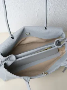 Detailed view of the light blue leather tote bag interior compartments and zipper pocket.