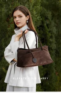 Brown suede shoulder bag detail view showing soft texture, double handles, and elegant design.