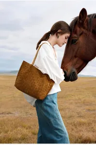 Detailed lifestyle scene showing brown woven shoulder tote bag texture outdoors in field.