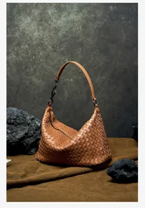 Detailed shot of brown leather woven shoulder bag, showcasing premium texture and craftsmanship.