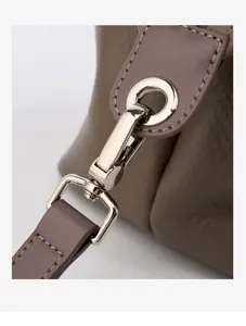 Close-up detail of premium leather handbag strap and shiny silver metal hardware clasp connector.