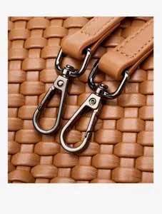 Close-up detail view of brown woven leather handbag strap and dark metal lobster clasp.