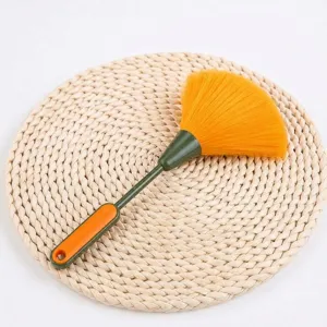 Detailopname van de plastic schoonmaakstofdoek met gele haren en groene handgreep.