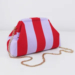 Détail rapproché du sac pochette en tricot rayé rouge et violet avec chaîne dorée.