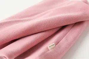Roze geribbelde stof detail van winterse halswarmer sjaal, zachte textuur close-up.
