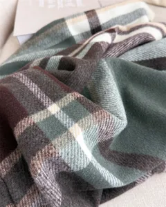 Close-up detail shot of retro plaid cashmere-feel scarf, soft green and brown winter neck warmer.