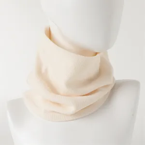 Close-up detail van de zachte gebreide beige nekwarmer, met comfortabele geribbelde textuur.