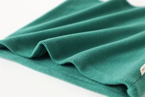 Detailfoto van groene geribbelde winternekwarmer met zachte stoftextuur en dubbele laag.
