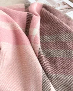 Close-up detail of soft pink and brown plaid imitation cashmere winter scarf texture.