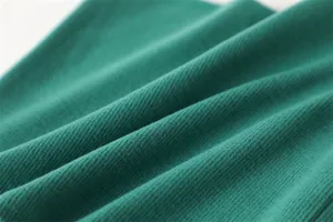 Een gedetailleerde close-up van de groene gebreide nekwarmer stof met zachte warme textuur