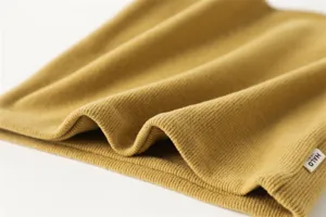 Close-up van de gele gebreide nekwarmer textuur, zacht gezellig materiaaldetail opname.