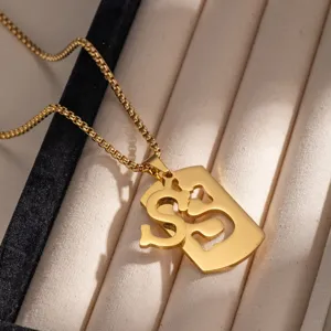 Primo piano di una collana con ciondolo a lettera vuota in acciaio inossidabile dorato su vassoio.