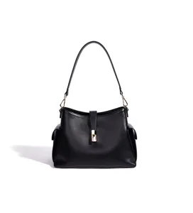 Detalle de bolso de hombro de cuero negro con cierre metálico y bolsillos laterales.