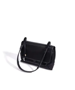 Vista detallada del bolso de hombro de nailon negro con solapa y elegante colgante de llave.