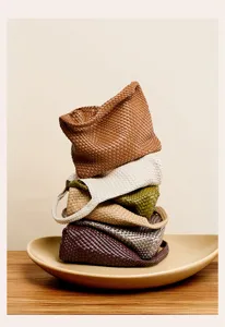 Detail view of colorful handmade woven shoulder bags stacked elegantly on a decorative plate.