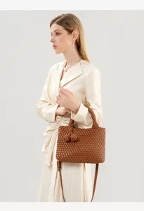 Detailed shot of a brown woven leather handbag showcasing artisanal intrecciato craft and knot.