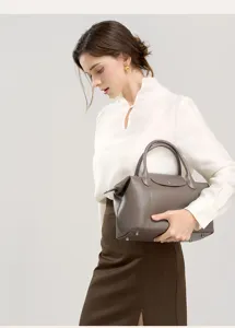 Detailed view of the elegant leather handbag held by a model in a bright studio scene.